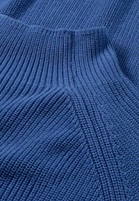 Stickad blått tyg med växlande ribbade och släta texturer, som har en medelhög tjocklek och jämna stygn genom hela.