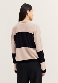 Strickpullover mit einem Farbblockdesign in Beige und Schwarz, mit Kragen und gerippten Bündchen. Weicher Stoff und lässige Passform.