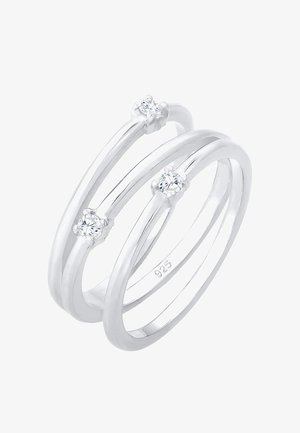 Tre anelli interconnessi realizzati in argento sterling lucidato (925), caratterizzati da tre piccole gemme tonde e trasparenti spaziati uniformemente.