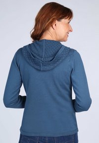 Blaues Hoodie mit einer strukturierten Strickkapuze, langen Ärmeln und lockerer Passform. Der Stoff ist weich mit einer glatten Oberfläche und dezenten Nahtdetails.