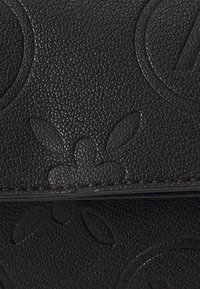 Black leather bag featuring an embossed design with floral and circular patterns, displaying a textured surface and subtle shine.
