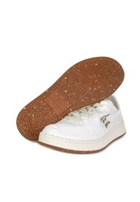 Sneakers bianchi in tela con suola in gomma color crema. La suola presenta un motivo floreale, mentre la parte superiore ha dettagli di cucitura e un logo.
