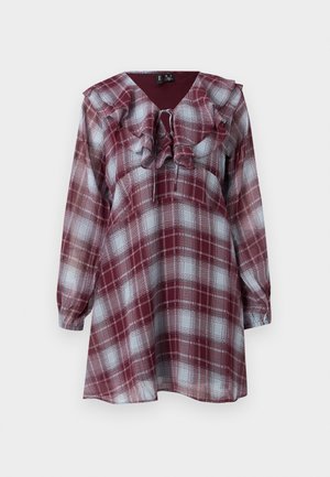 Rochie cu mânecă lungă, în carouri roșii și albastre, cu un decolteu în V volanat și o croială lejeră. Fabricată dintr-un material ușor, cu o textură netedă.