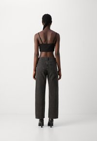 Top negro cropped y jeans de mezclilla oscura de cintura alta con un corte recto. Los jeans tienen dos bolsillos traseros y costuras visibles.