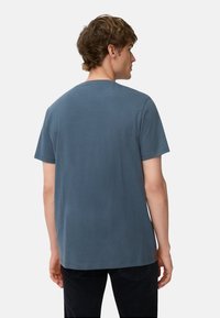 Blå bomulds-t-shirt med rund hals, korte ærmer og en ensfarvet ryg. Stoffet fremstår blødt med en glat tekstur.