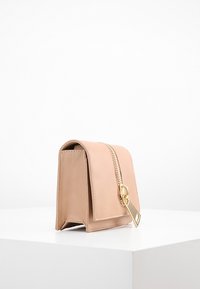 Naga skórzana torba o strukturalnym kształcie, teksturowanym wykończeniu i złotym zamku błyskawicznym. Posiada klapę do złożenia oraz płaskie dno dla stabilności.