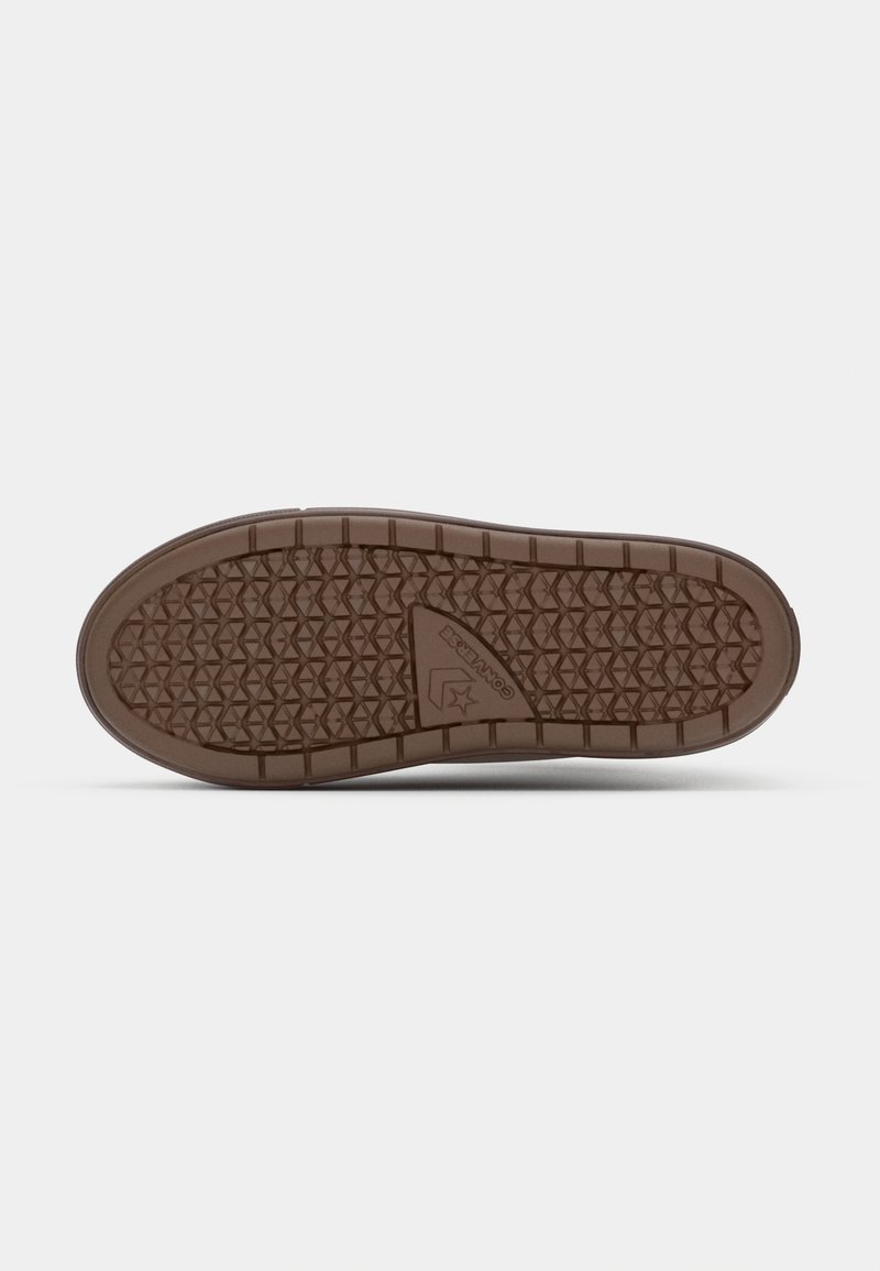 Bruine rubberen zool van een schoen met een gestructureerd diamantpatroon voor grip en een logo detail nabij de voetboog.