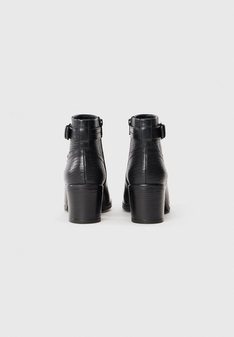 Bottines en cuir noir avec une finition texturée, une sangle ajustable avec une boucle en métal et un talon épais et haut.