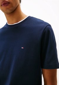 T-shirt in cotone blu navy a maniche corte, con un colletto bianco a contrasto e un piccolo logo ricamato sul petto. Tessuto liscio.