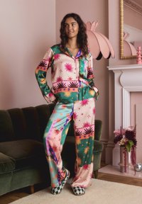 Seidiger Pyjama-Set mit einem bunten Sonnen- und Sternenmuster in Pink, Grün und Orange. Besteht aus einem Oberteil mit Knöpfen und locker sitzenden Hosen.