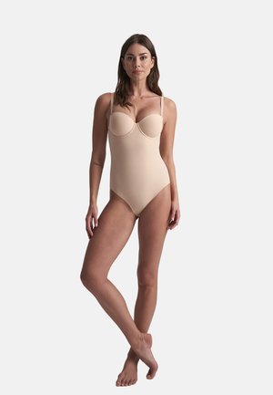 Beige yksiöinen uimapuku, jossa on jämäkkä yläosa, säädettävät hihnat ja sileä pinta. Siinä on sydänleikkauksellinen pääntie ja korkea lahje.