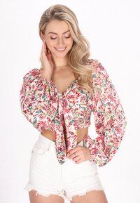 Blomster crop top med puffede ærmer i hvidt stof med farverige mønstre. Kombinationen med højtaljede hvide denimshorts.