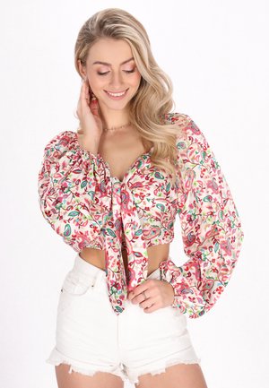 Virágmintás, puffos ujjú fehér crop top, színes nyomatokkal. Magas derékú fehér farmer sorttal párosítva.