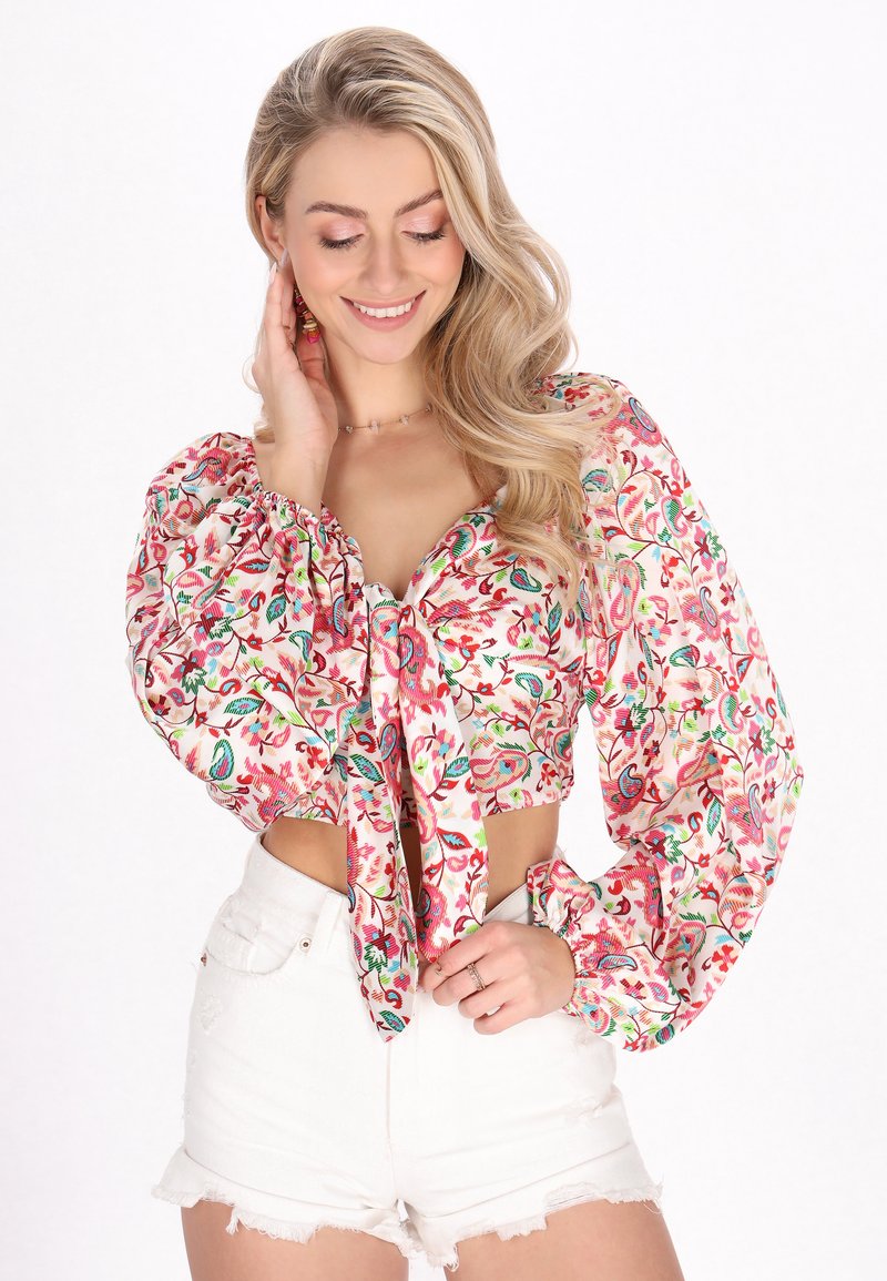 Top scurt floral cu mâneci bufante din material alb, având imprimeuri colorate. Asortat cu pantaloni scurți din denim alb, cu talie înaltă.
