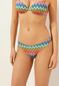 Flerfärgad bikiniuppsättning med ett zigzagmönster i livliga nyanser av röd, grön, blå och orange; slät textur, med stöd av wiren.