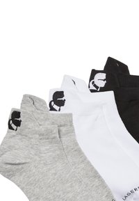 Conjunto de tres pares de calcetines tobilleros de algodón en gris, blanco y negro, con un diseño de logo en contraste en la zona del talón.