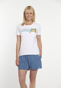 Hvid kortærmet t-shirt med grafisk print, der viser grønne blade og frugtskiver. Kombineret med lyseblå shorts. Casual design.