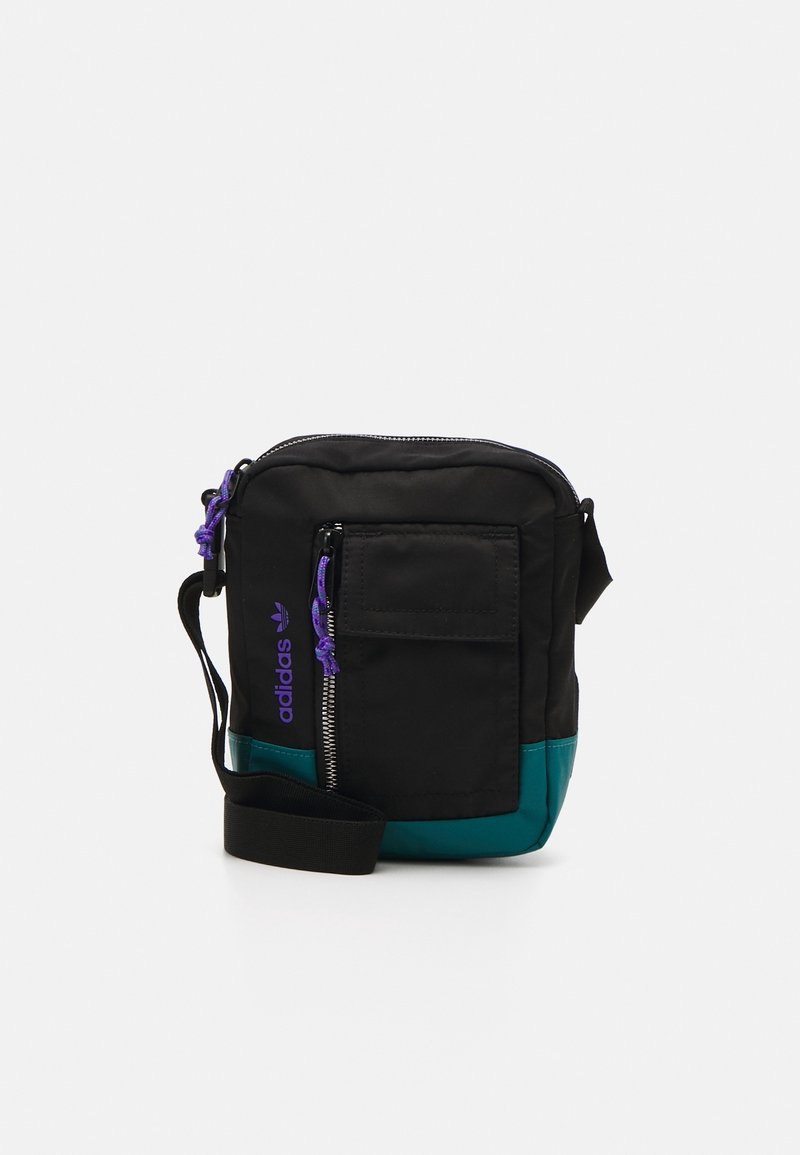 Svart och teal crossbody-väska med dragkedja, justerbar rem, framficka och lila logotypdetalj. Tillverkad av slitstarkt tyg.