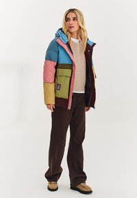 Pestrobarevná péřová bunda s modrou kapucí, růžovými a zelenými panely a vínovou částí. Má zipové zapínání a přední kapsu.