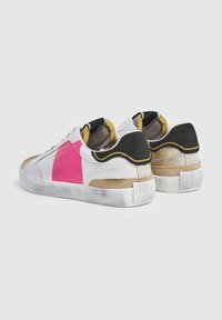 Zapatillas blancas con acentos en rosa, negro y beige. Materiales de ante y piel. Diseño de tipo bajo con suelas texturizadas. Logo estampado en los talones.