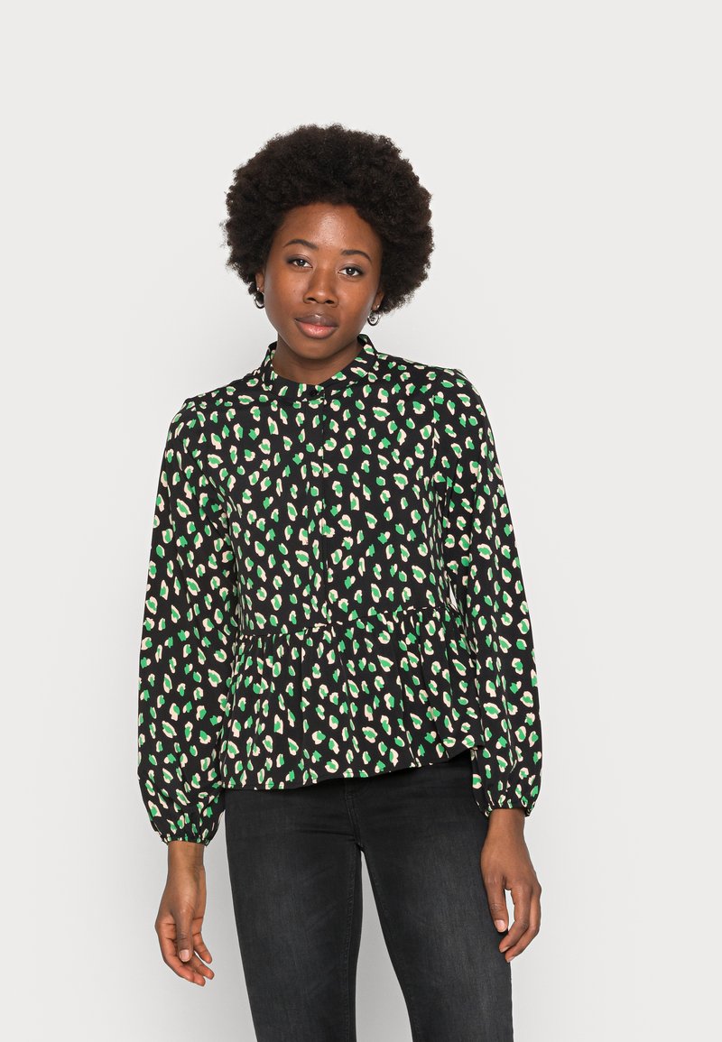 Blusa peplum preta com manchas verdes e creme, apresentando um decote redondo e mangas compridas com punhos franzidos. Textura de tecido suave.