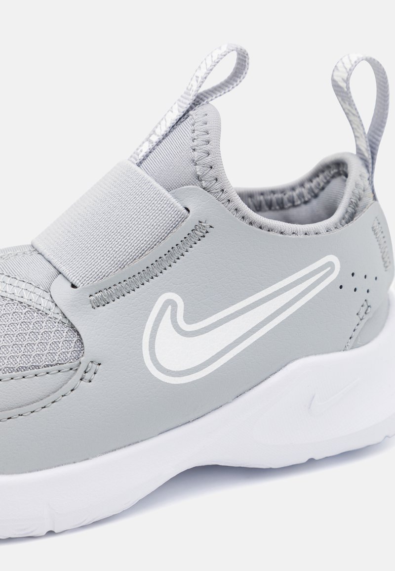 Grijze instapsneaker met een gestructureerde mesh-bovenkant, elastische band en wit Nike swoosh-logo. Beschikt over een gevoerde kraag en rubberen zool.