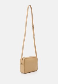 Borsa a tracolla in pelle marrone chiaro con forma rettangolare, chiusura con zip e una tracolla sottile e regolabile. Texture liscia, design minimalista.