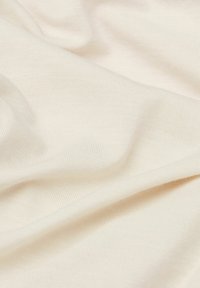 Crème-kleurige stof met een zachte, gladde textuur, voorzien van een subtiel ribpatroon en een lichte drapeer. Geschikt voor kleding of meubels.