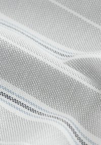 Textil mit einem hellgrauen gewebten Muster und weißen, hellblauen und dunkelblauen Streifen. Weiche Textur mit sichtbarem Webdetails.