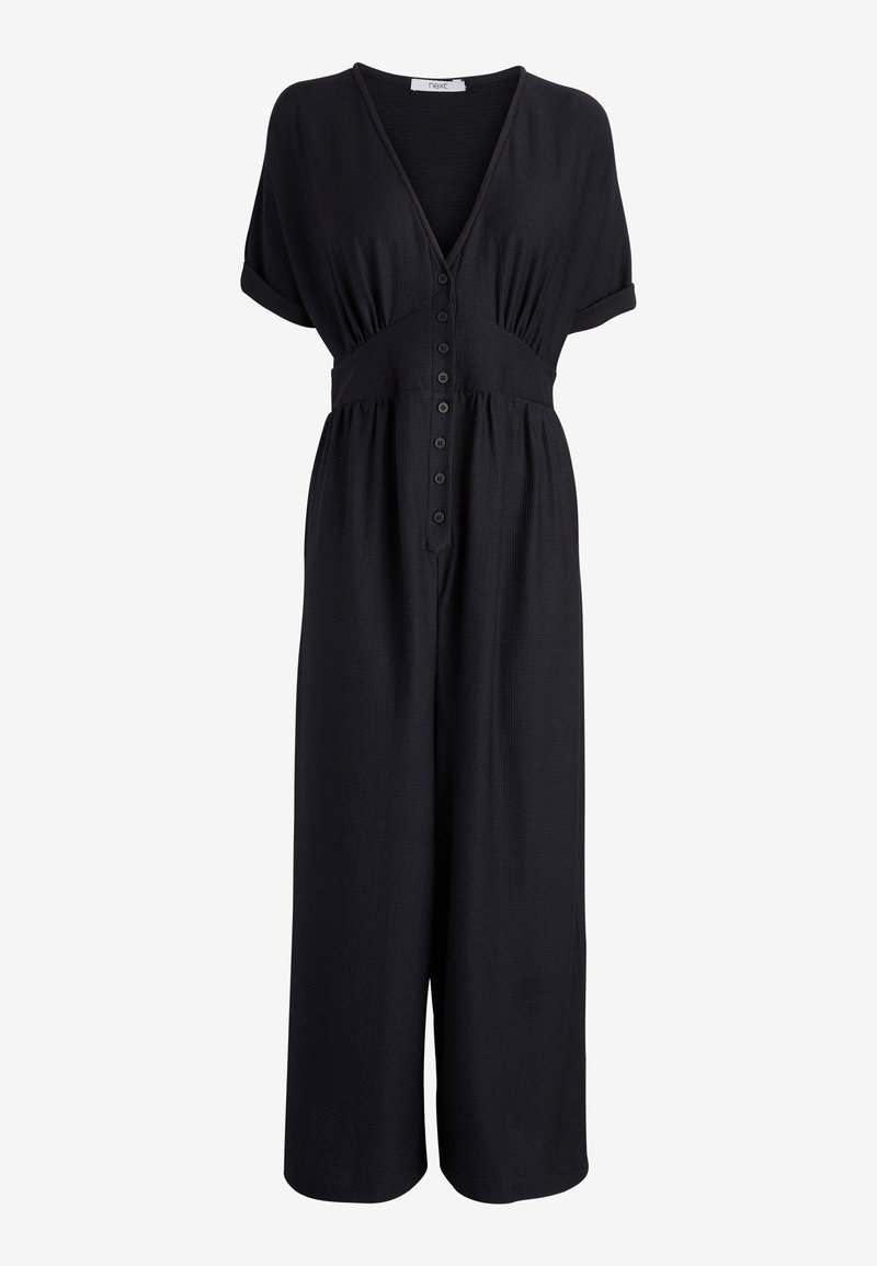 Combinaison noire à manches courtes avec un profond décolleté en V, fermeture boutonnée devant, taille froncée et pantalon large raccourci.
