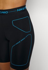 Czarne spodenki Nike Pro z niebieskimi liniami akcentowymi, o dopasowanym kroju i elastycznym pasie z nazwą marki.