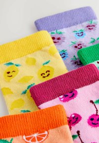 Värvikad sokid naeratavate puuviljamustritega, mis hõlmavad sidruneid, kirsse, viinamarju ja apelsiniviile valgel pinnal.