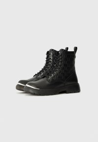 Black lace-up boots with a textured side panel and metallic accent on the toe. Features a rugged sole and pull tab for easy wear.