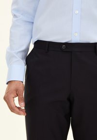 Dunkle maßgeschneiderte Hosen mit glatter Textur, ausgestattet mit einem Knopfverschluss und Gürtelschlaufen, kombiniert mit einem hellblauen Langarmhemd.