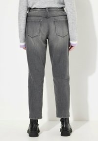 Jean en denim gris avec une coupe fuselée, cinq poches et couture visible. La ceinture est dotée d'un élastique pour un confort accru.