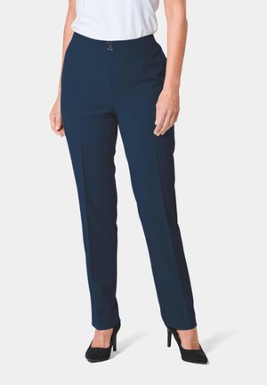 Pantalon ajusté bleu marine avec une texture lisse, doté d'une fermeture éclair devant et d'une coupe élégante. Associé à des chaussures à talons hauts noires.
