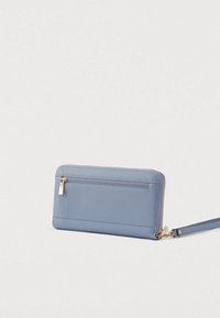 Gaiši zils makā ar rāvējslēdzēju, izgatavots no teksturēta sintētiska materiāla, ar zelta krāsas rāvējslēdzēju, plaukstas siksniņu un aizmugurējo ārējo kabatu.