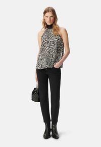 Top a collo con stampa leopardata e collo nero, abbinato a pantaloni aderenti neri e stivaletti alla caviglia. Accessori: una piccola borsa nera.