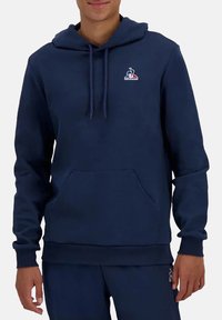 Felpa blu navy realizzata in tessuto morbido, con tasca frontale, cappuccio regolabile con cordino e un piccolo logo sul petto.