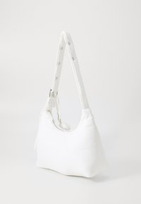 White fabric handbag with a curved shape, padded strap, and silver hardware. Features a zipper closure and smooth texture.