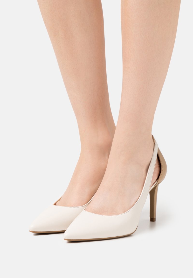 Bílé kožené lodičky na vysokém podpatku s špičatou špičkou a otevřenou patou. Mají hladký povrch a štíhlý jehlový podpatek.