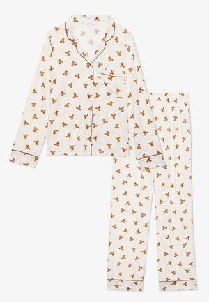 Witte pyjama set met lange mouwen en broek, voorzien van een overal patroon van oranje teddyberen en bruine piping langs de randen.