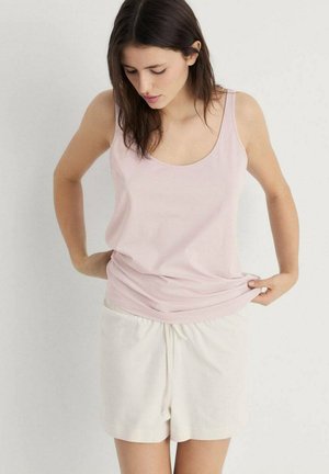 Hellrosa ärmelloses Oberteil aus weichem Stoff, kombiniert mit weißen Shorts mit Kordelzug. Das Outfit hat eine lockere Passform und eine glatte Textur.