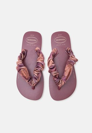 Paire de tongs texturées mauves avec des brides en tissu froncées et le logo Havaianas visible sur fond blanc.