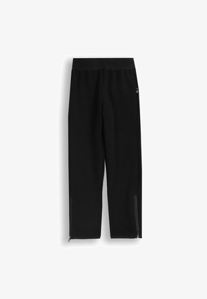 Czarne spodnie sportowe o zwężanym kroju, z elastycznym paskiem w talii i zamkami błyskawicznymi przy mankietach; wykonane z miękkiego materiału o gładkiej fakturze.