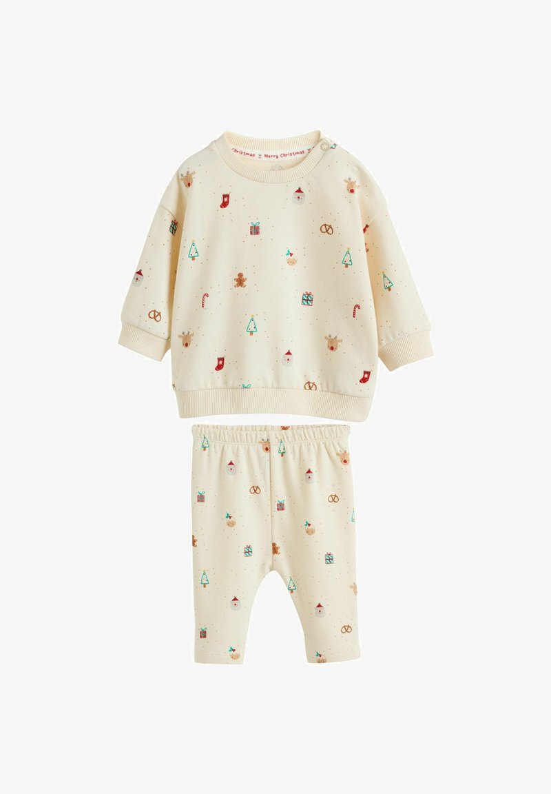 Tenue de bébé couleur crème avec manches longues et pantalon, décorée de petites icônes de Noël comme des sapins, des cadeaux, du pain d'épices, des cannes en sucre d’orge et des rennes.