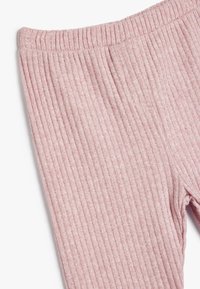 Leggings rossi con costine, dotati di una superficie strutturata e di una vita elastica. Il tessuto presenta una leggera lucentezza e strisce verticali.