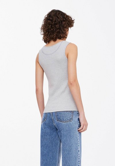 Grijze mouwloze top van zachte stof, aansluitende pasvorm, ronde halslijn, gecombineerd met lichtblauwe high-waisted spijkerbroek.
