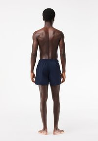 Marineblaue Badeshorts mit einem elastischen Bund, gefertigt aus leichtem Stoff. Die Shorts haben ein schlichtes, unverziertes Design.