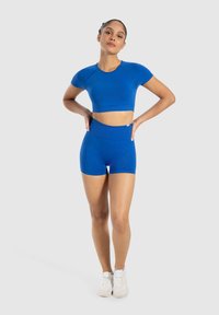 Top corto sportivo blu e pantaloni corti a vita alta, realizzati in materiale elastico. Texture liscia, design aderente e maniche corte.